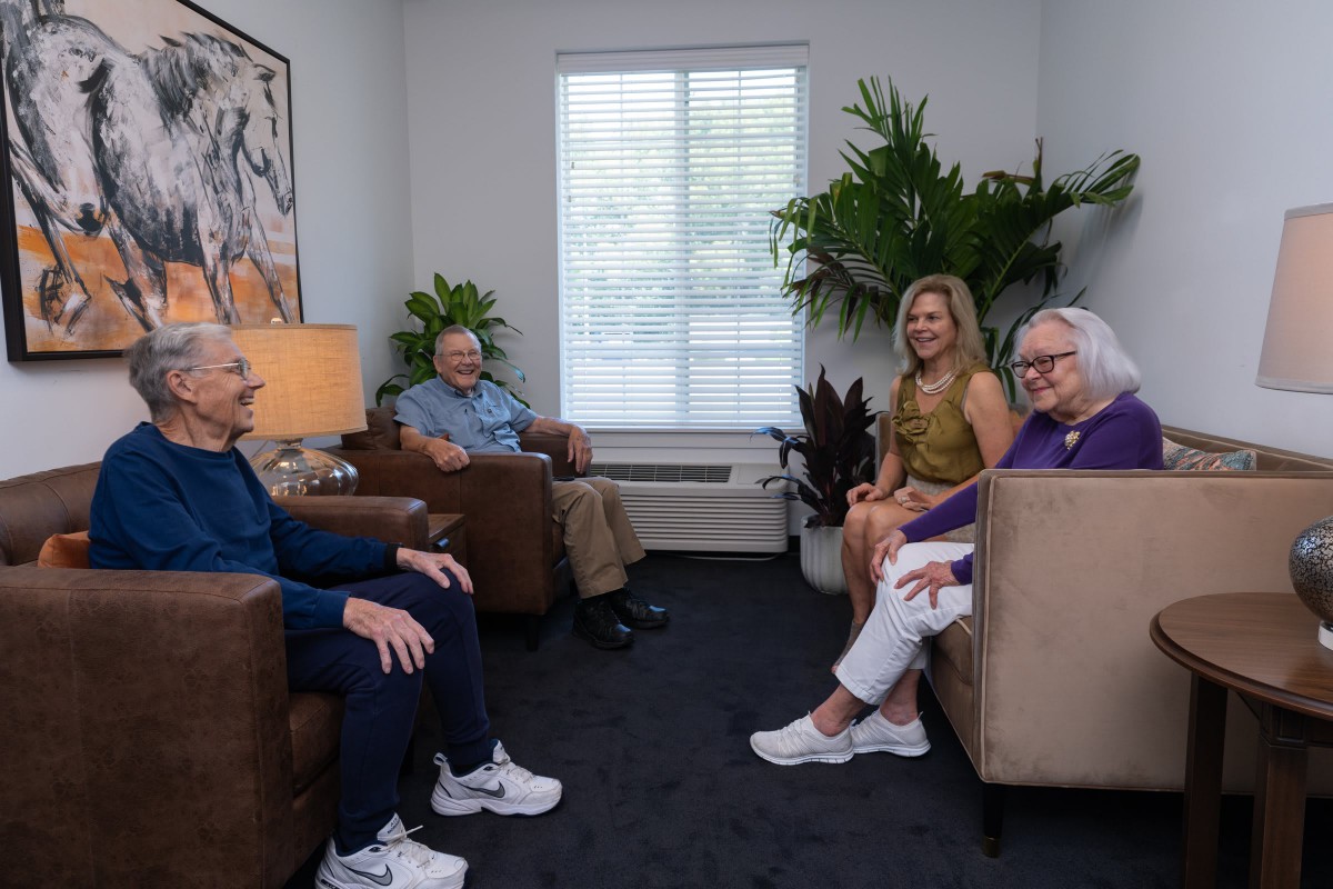 A group of seniors relaxing and conversing in a cozy indoor setting.