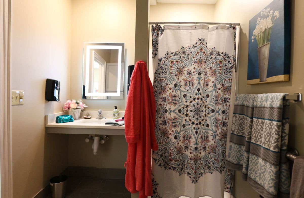 A cozy bathroom with a patterned shower curtain and a red towel hanging.