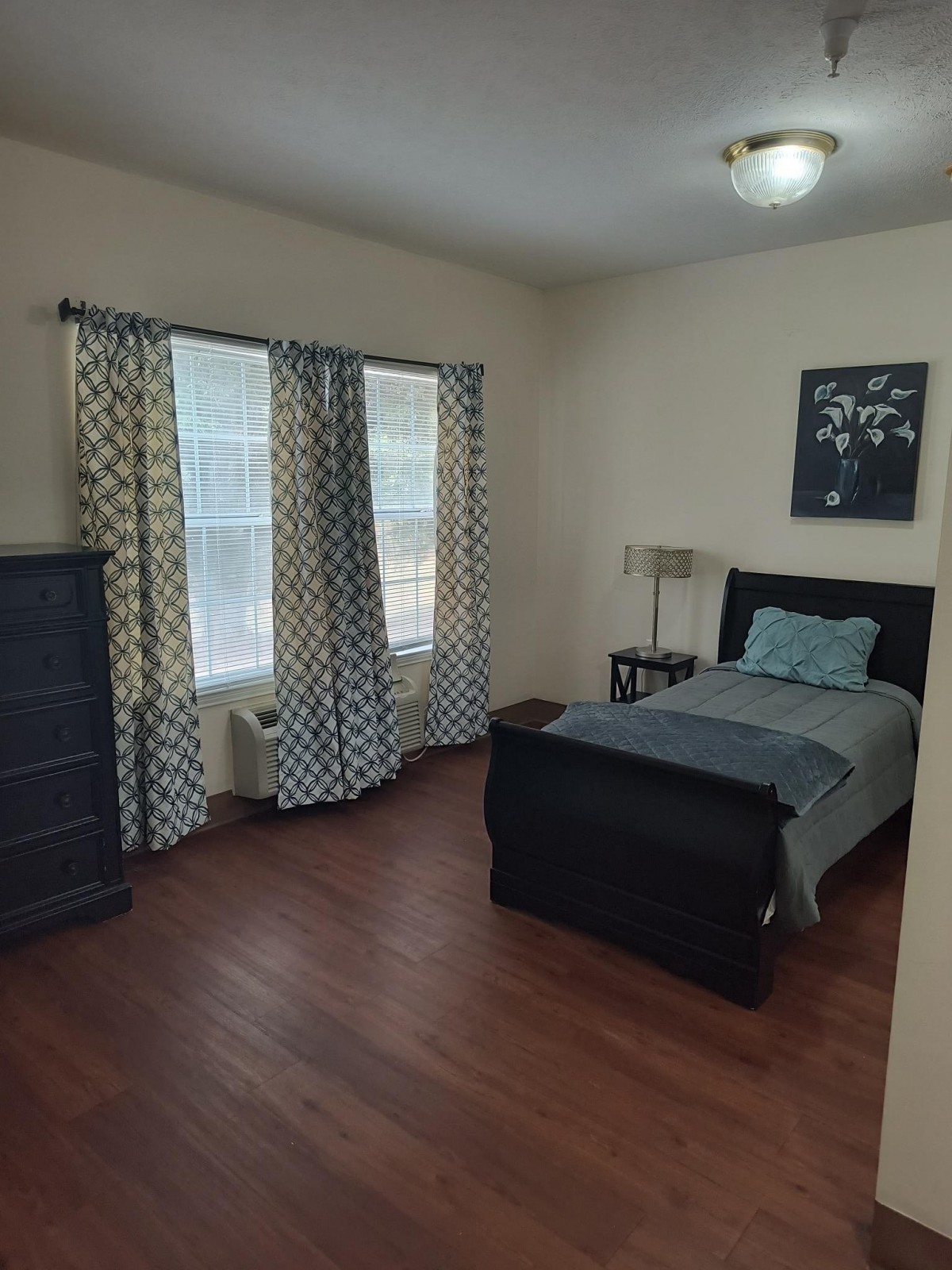 A neatly arranged bedroom with a single bed and a dresser.
