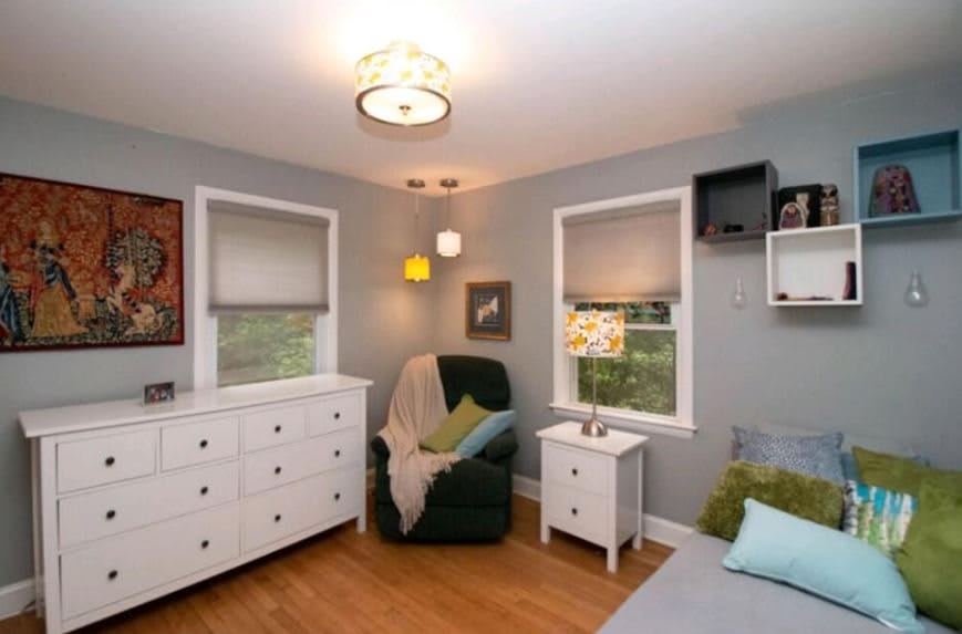 A cozy bedroom with a dresser, armchair, and nightstands.