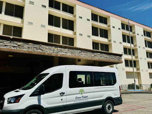 A shuttle van parked in front of a hotel building, ready to transport guests.
