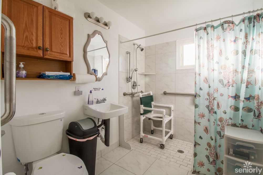 An accessible bathroom equipped with a shower chair and grab bars for safety.