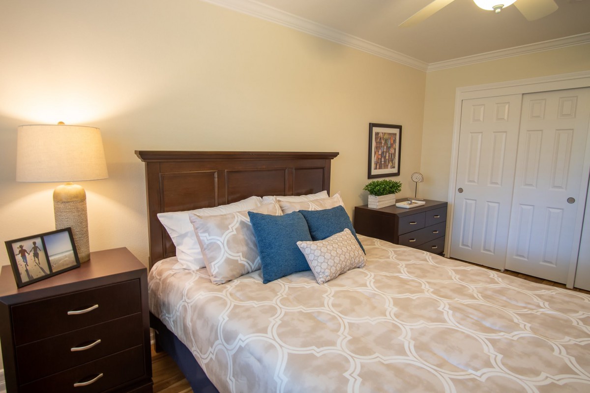 A cozy bedroom with a wooden headboard, patterned bedding, and decorative pillows.