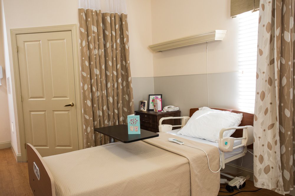 A clean and organized hospital room with a bed, side table, and curtains.