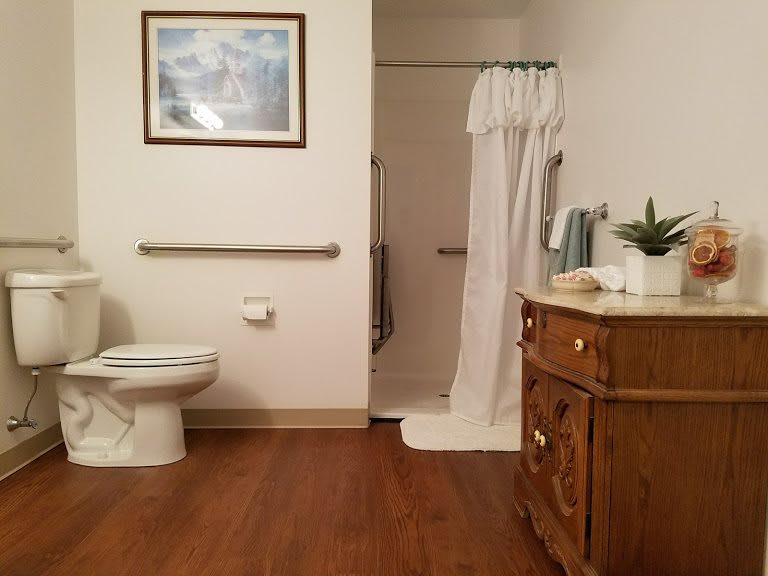 A clean and organized bathroom with a toilet, shower, and wooden vanity.