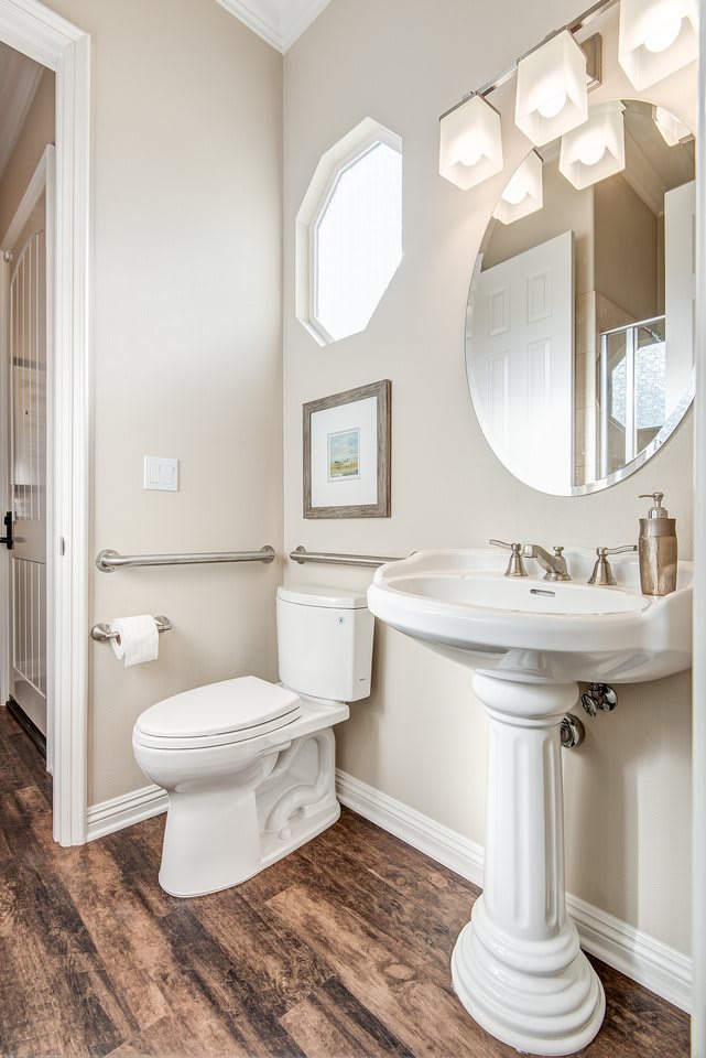 A bright and clean bathroom with a pedestal sink and wall-mounted mirror.