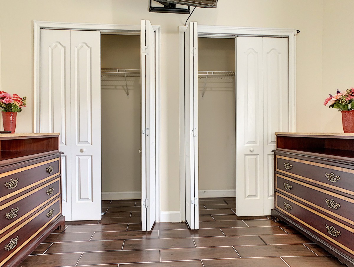 A room with open closet doors flanked by wooden dressers.