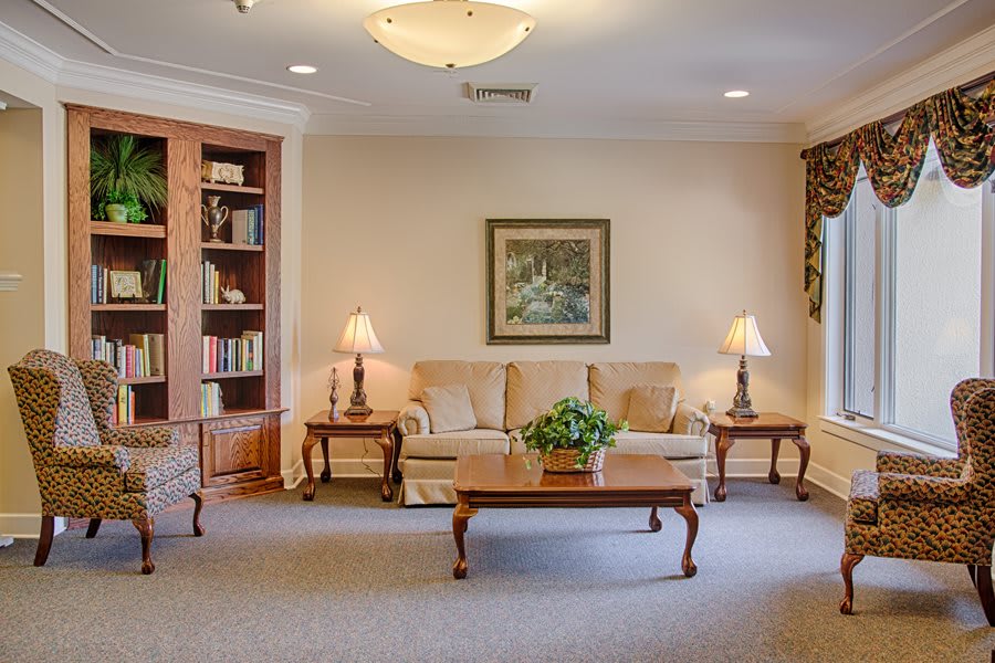 A cozy living room with a sofa, coffee table, lamps, and a bookshelf.