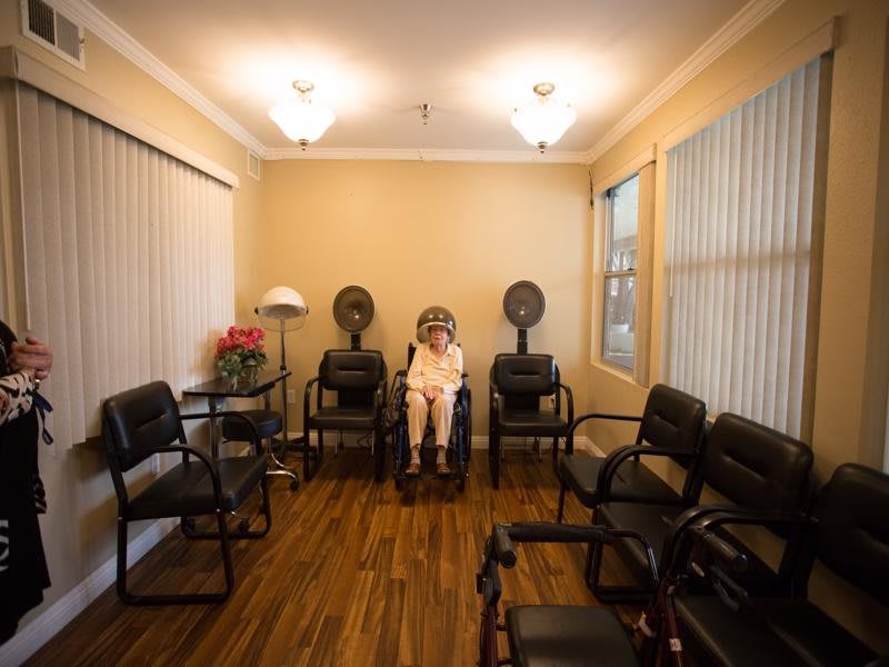 An empty hair salon waiting area with chairs and hair dryers.