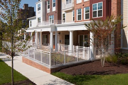 A modern residential building with a porch and railing.