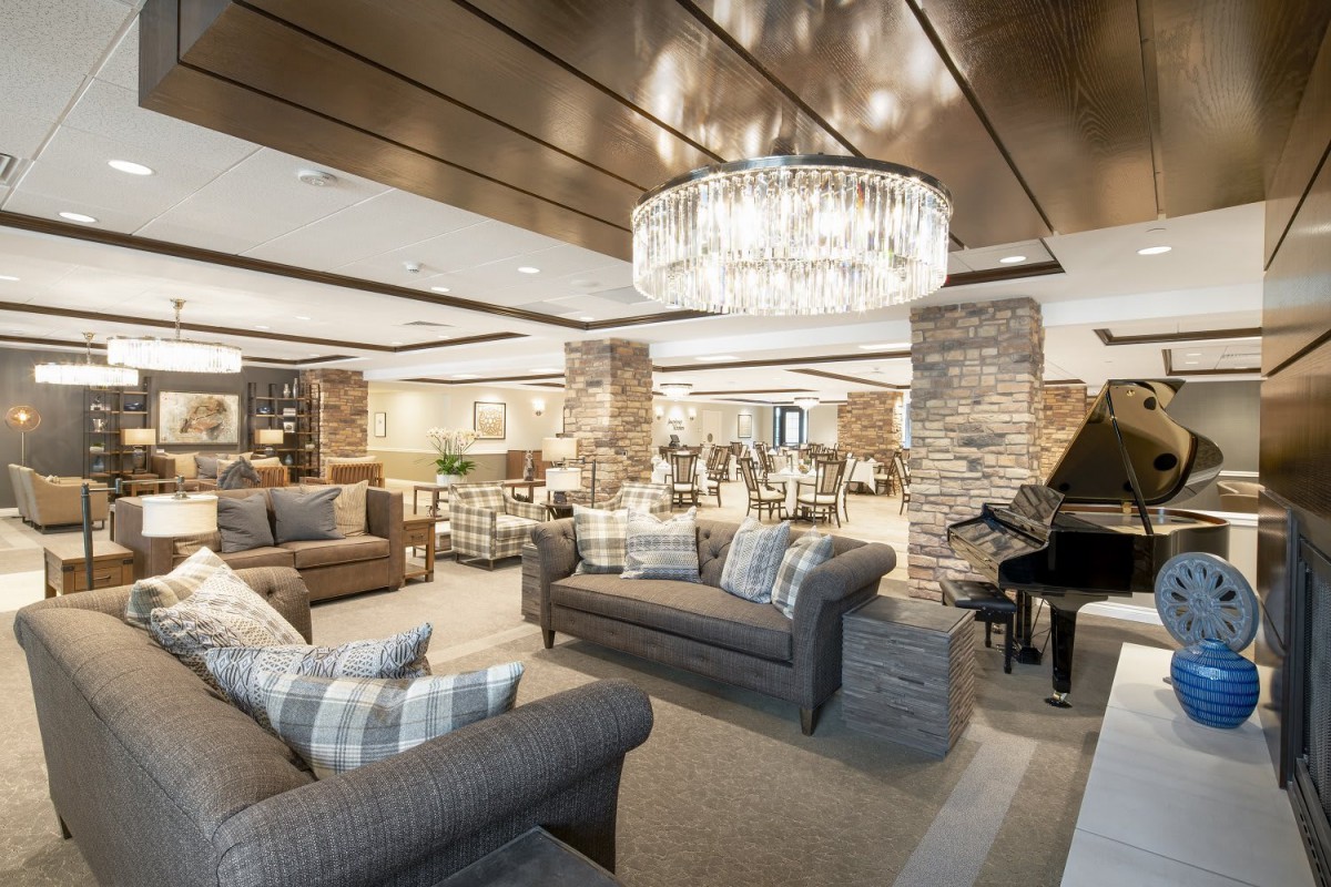 A luxurious living room with elegant sofas, a grand piano, and a stunning chandelier.
