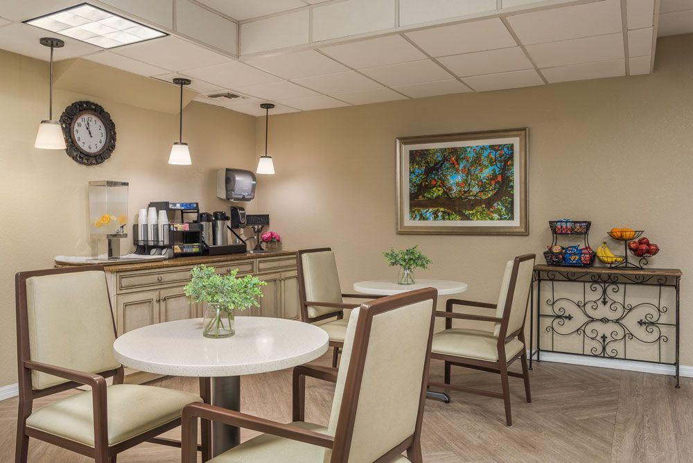 A cozy cafe area with tables, chairs, a coffee station, and decorative artwork on the wall.