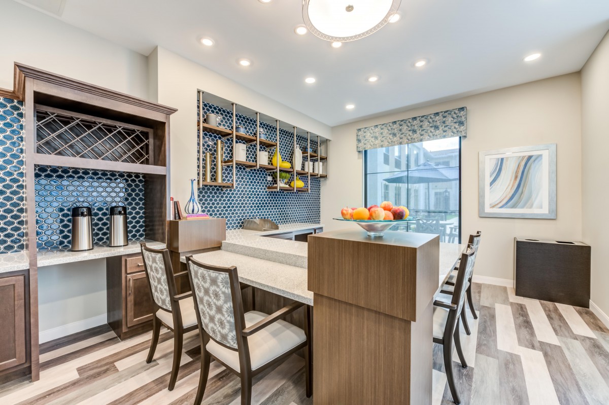 A modern kitchen with a bar area, featuring wood cabinetry and contemporary lighting.