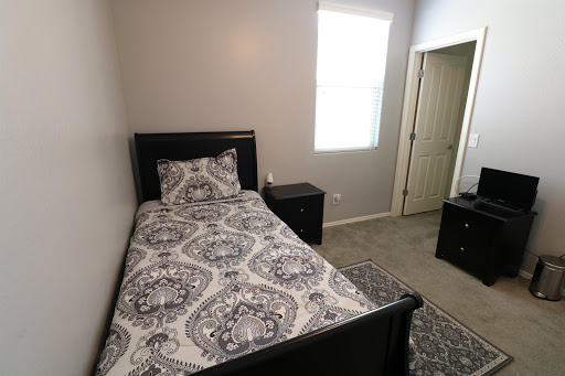 A cozy bedroom featuring a single bed with decorative bedding and black furniture.