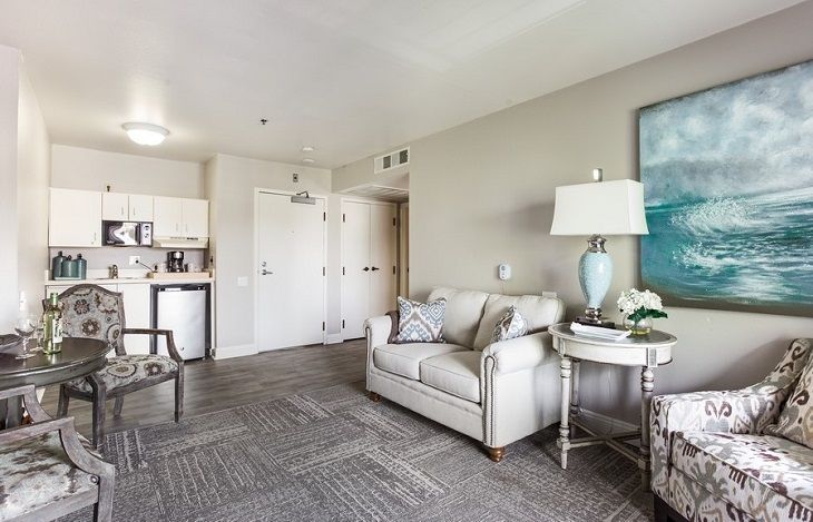 A modern living room with neutral tones featuring a comfortable sofa, side table with lamp, and wall artwork.