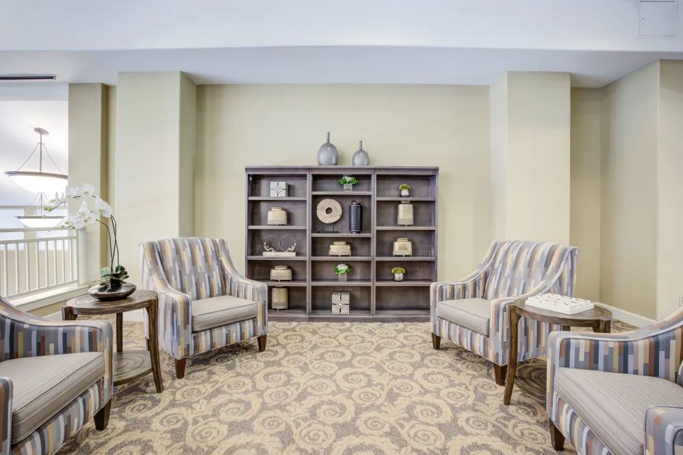 A cozy living room setting featuring striped armchairs and a decorative bookshelf.