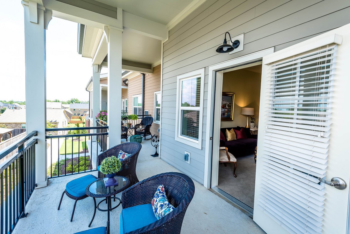 A cozy balcony with stylish outdoor seating and modern decor, offering a relaxing spot in an apartment setting.