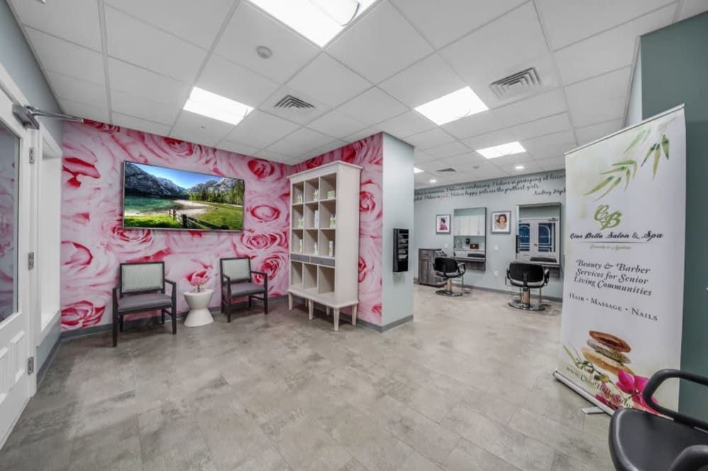 A modern salon interior with a vibrant pink floral wallpaper, featuring a waiting area with chairs and a hair styling station.
