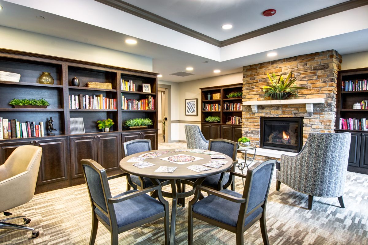 A cozy reading room with bookshelves and a fireplace.