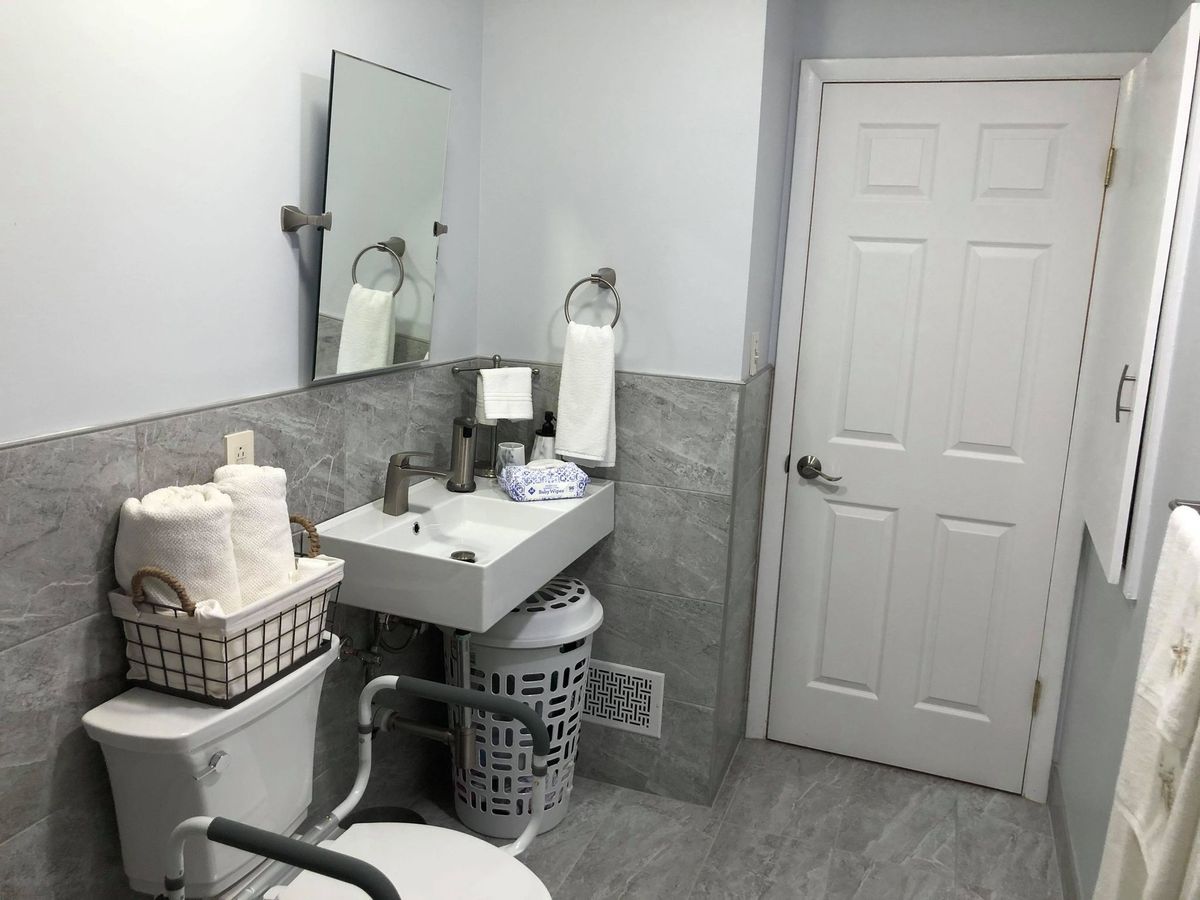 A clean and organized bathroom with a mirror, sink, toilet, and towels neatly arranged.