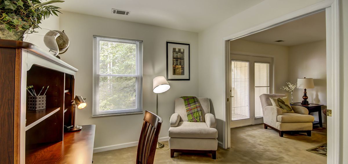 A cozy living room corner with a comfortable armchair, floor lamp, and window view.
