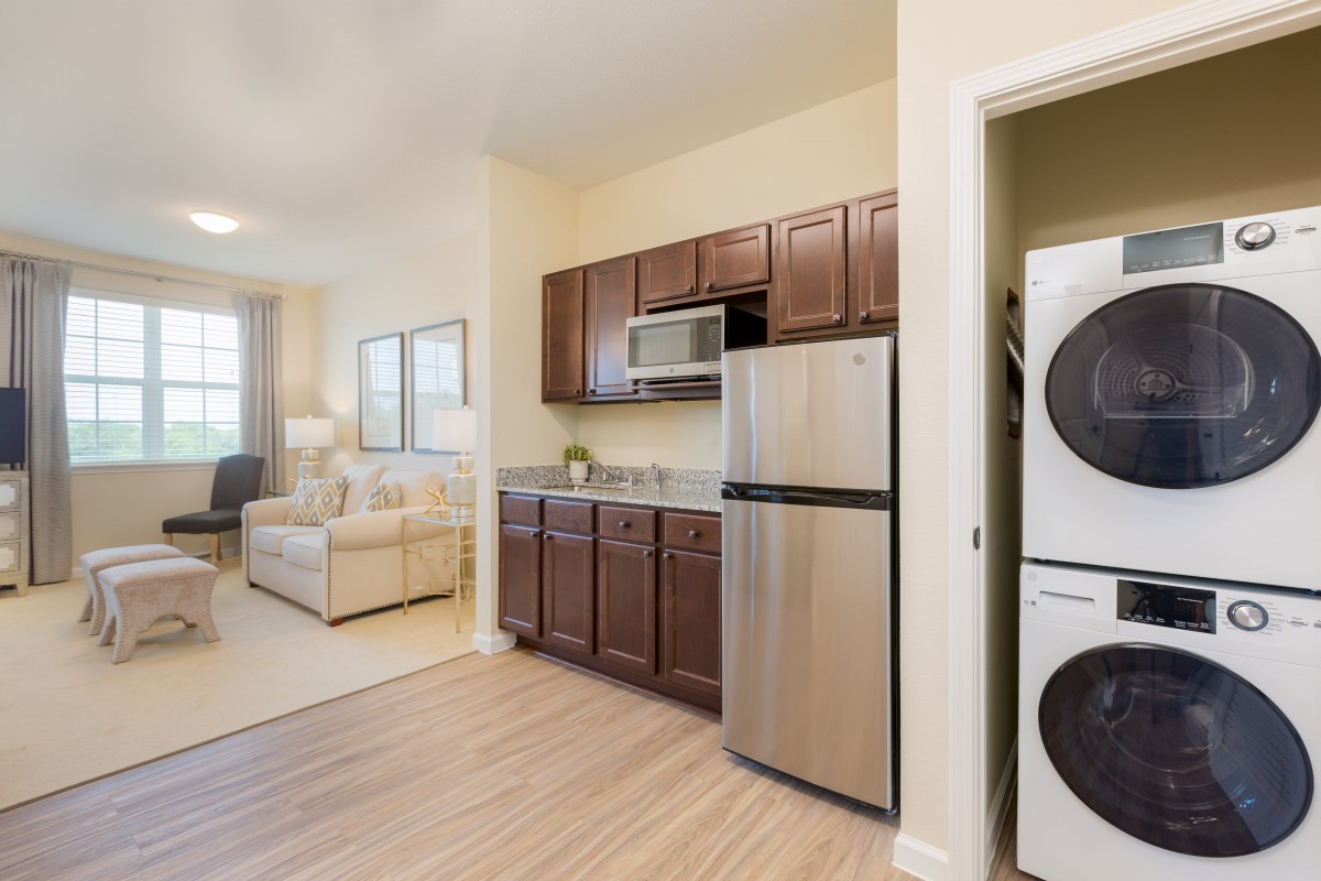 Modern apartment kitchen with stainless steel appliances and adjacent living area.
