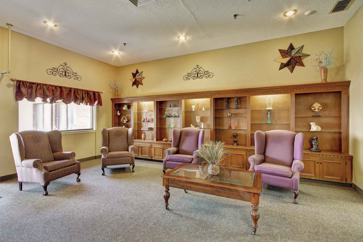 A cozy living room featuring armchairs, a wooden coffee table, and decorative cabinets.