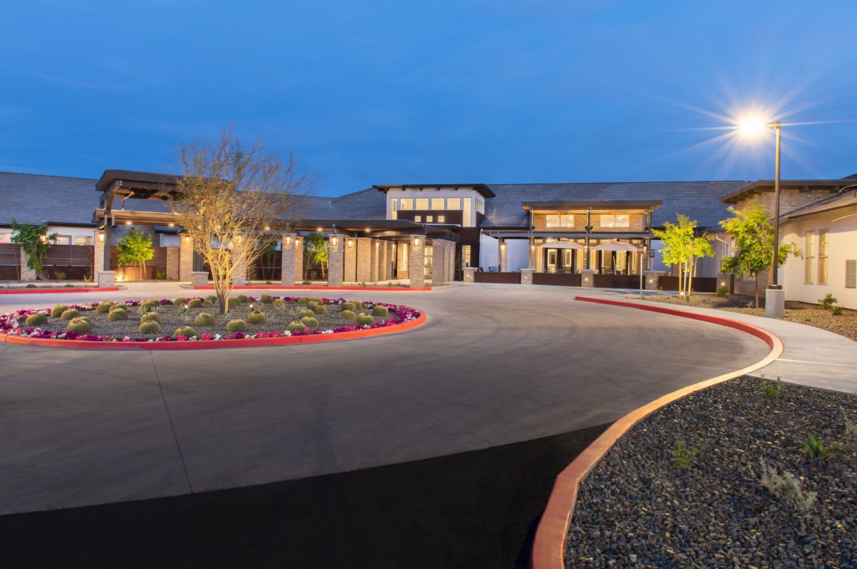 A luxurious mansion illuminated at night, featuring a circular driveway.