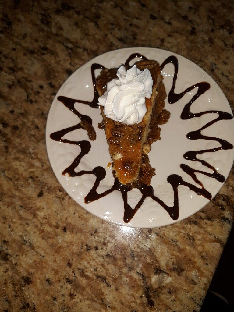 A slice of dessert cake topped with whipped cream and drizzled with chocolate sauce.