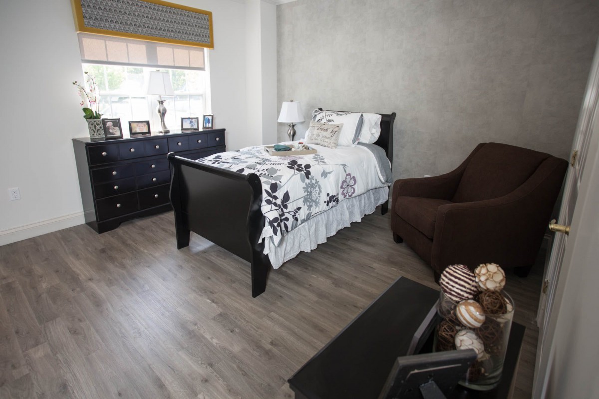 A modern bedroom with a single bed, dresser, and chair.