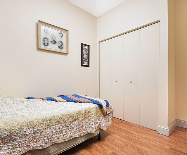 A cozy bedroom with a single bed, wooden floor, and framed artwork on the wall.