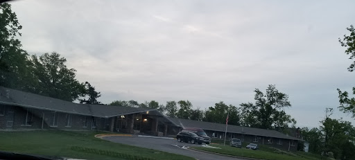 A cloudy day over a building with vehicles parked outside.