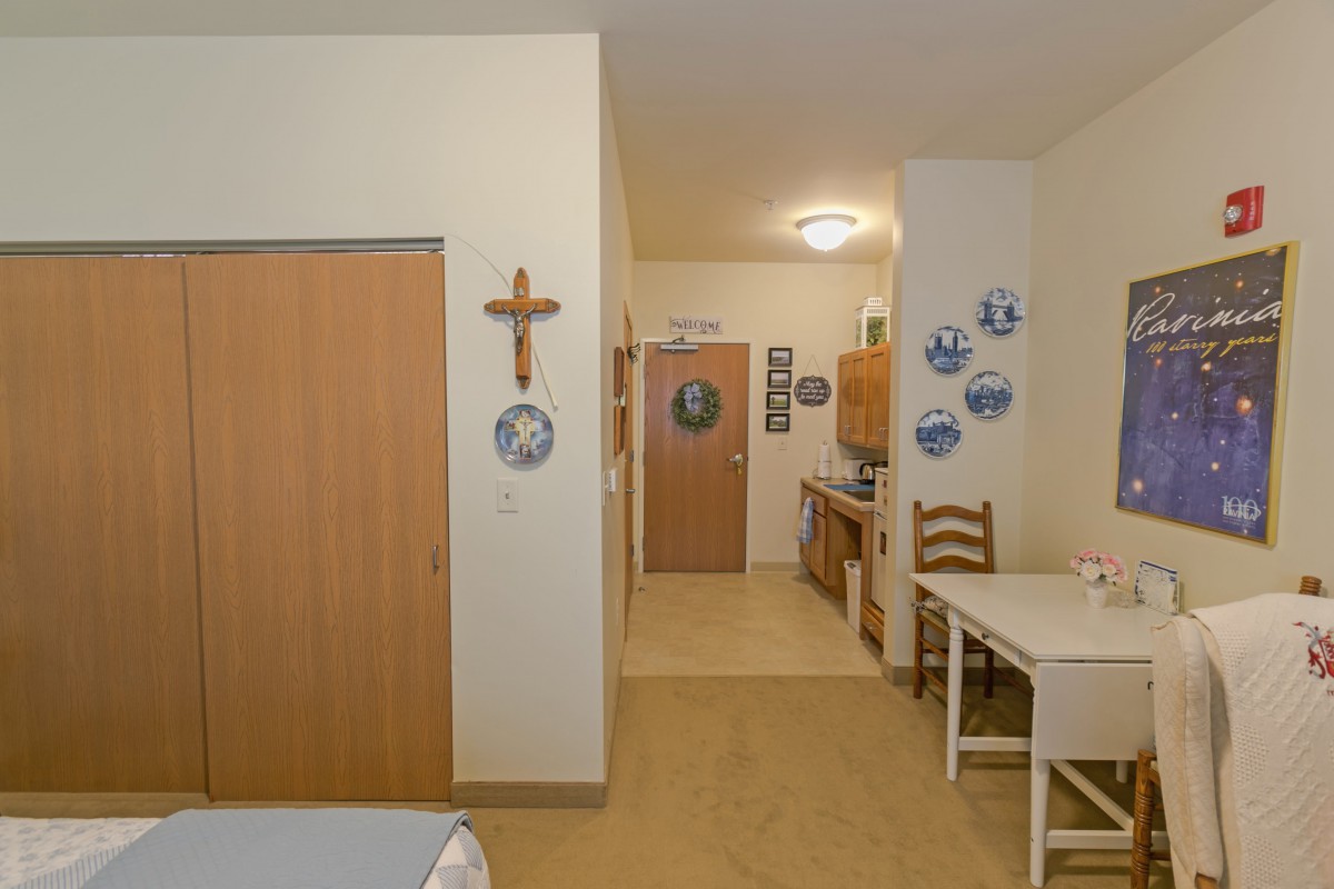 A cozy room featuring a kitchenette and dining area with wooden furniture and decorative wall plates.