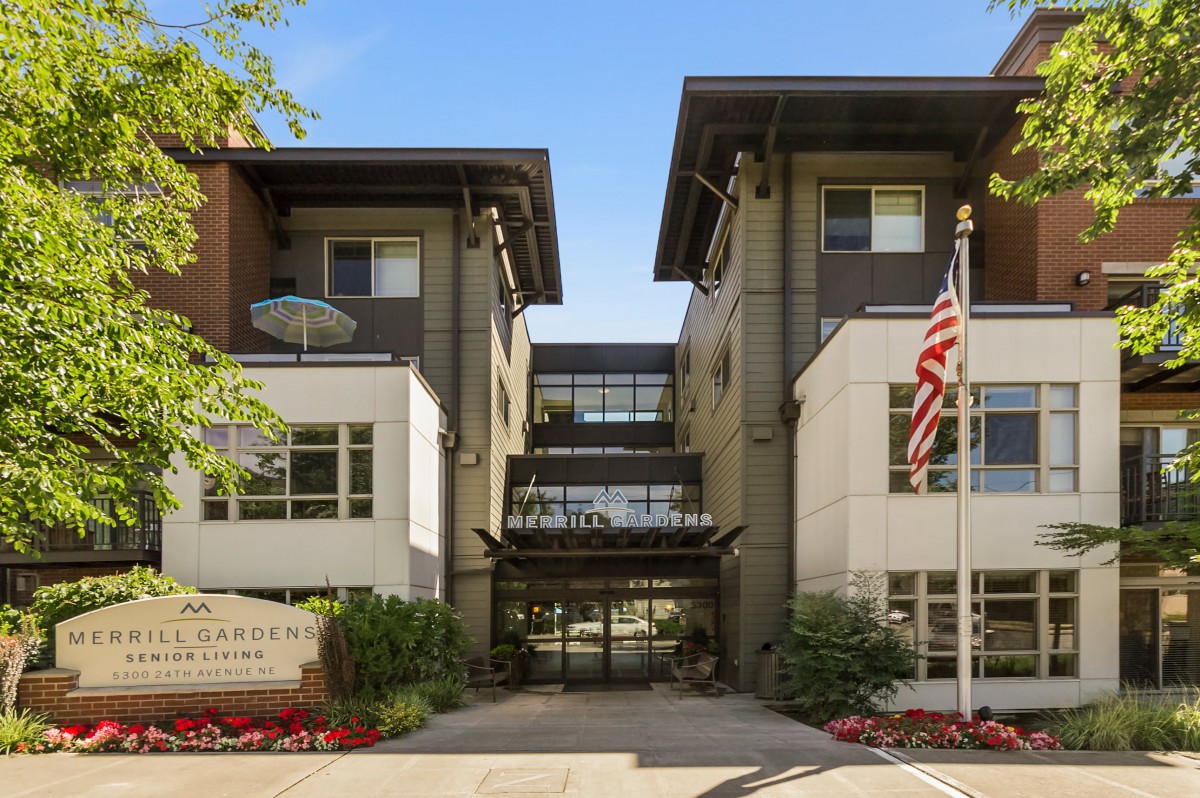 A modern building entrance with an American flag and well-maintained landscaping.