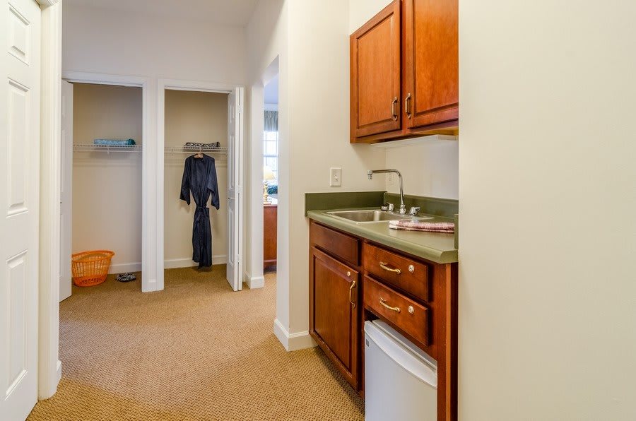 A cozy kitchenette with wooden cabinets and a compact fridge.