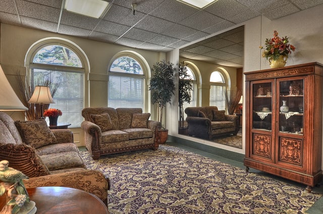 A cozy living room with sofas, a large mirror, and arched windows letting in natural light.