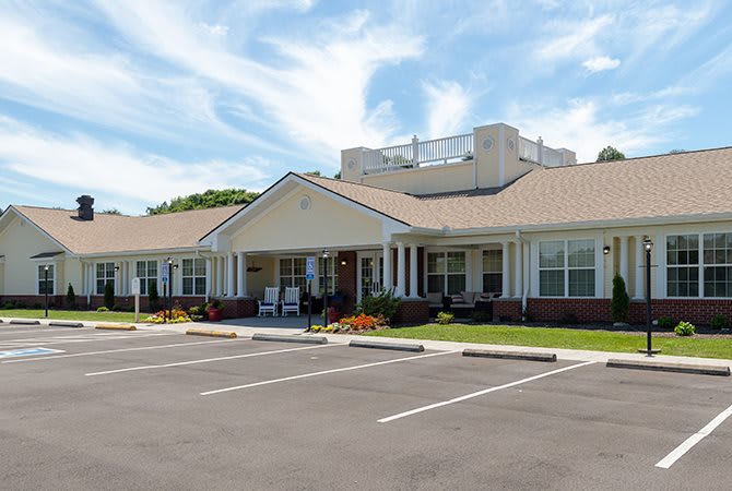 A single-story building with a parking lot under a blue sky.
