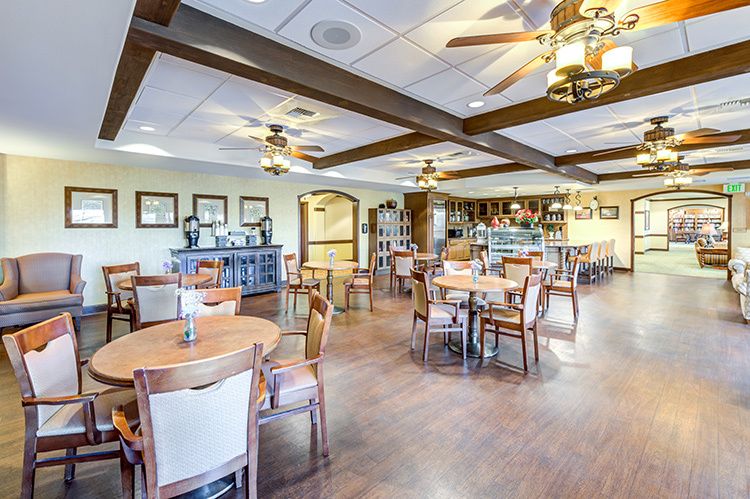 A spacious dining area with neatly arranged tables and chairs, featuring wooden flooring and elegant lighting.