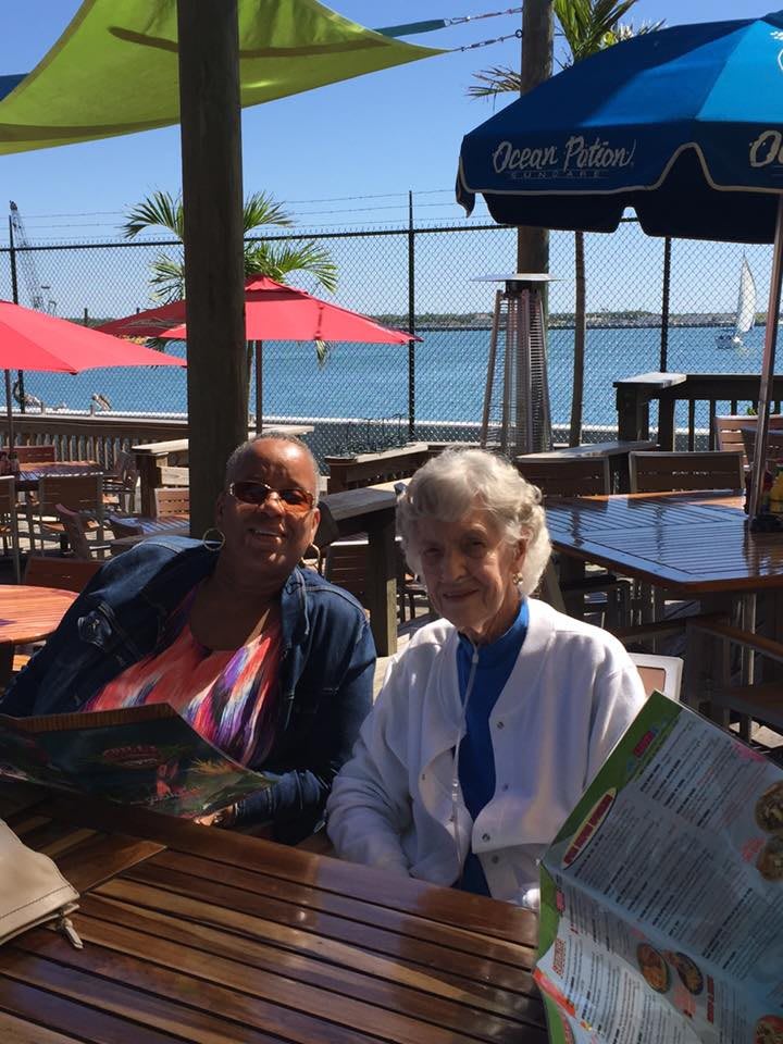 Two individuals sitting at an outdoor restaurant by the sea.