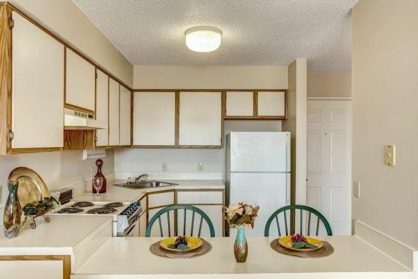 A compact kitchen with a dining area featuring two chairs and a countertop.