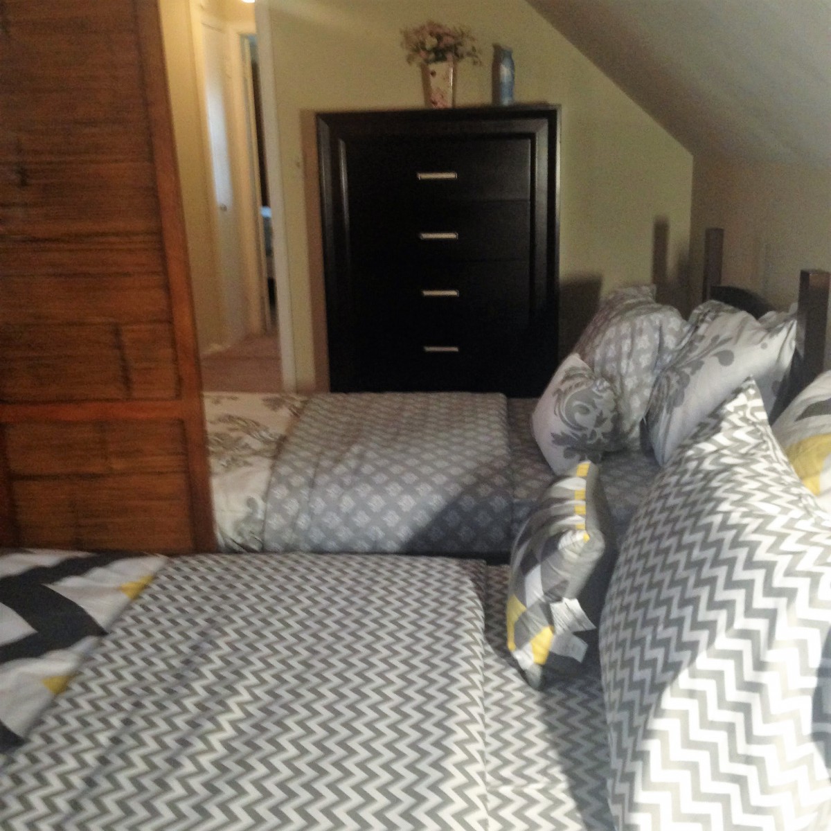 A cozy bedroom with a neatly made bed and a black dresser.