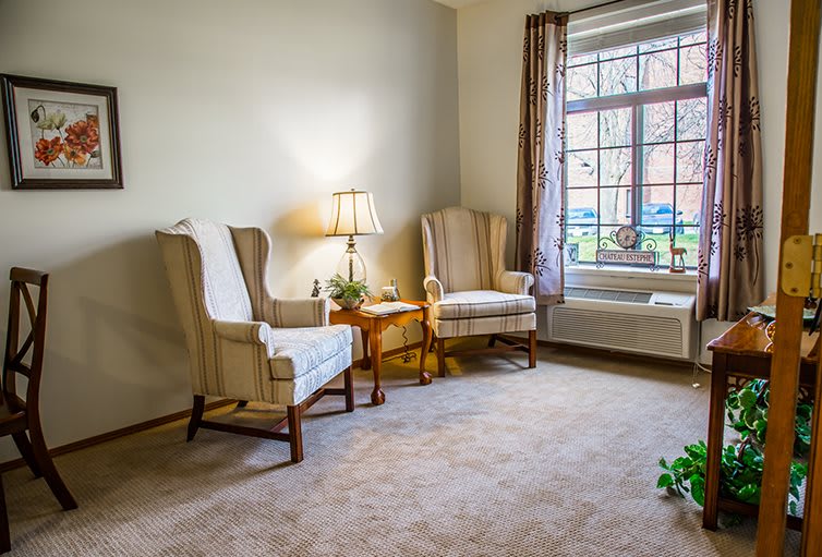 A cozy living room with two armchairs and a small table by the window.