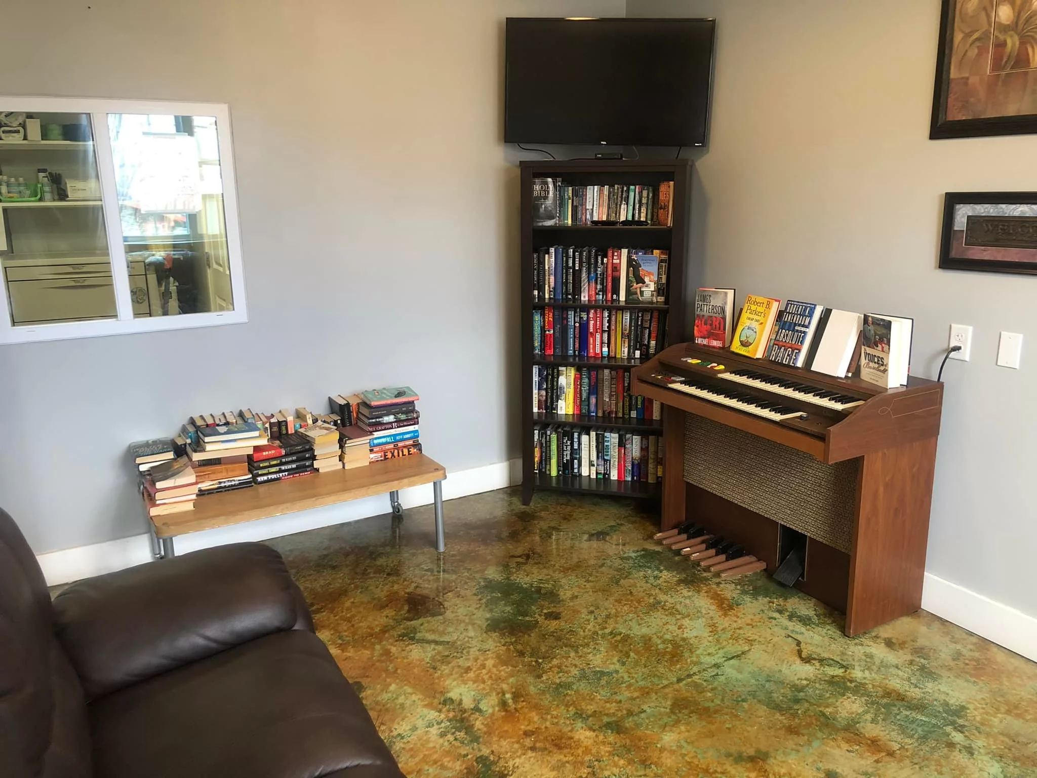 A cozy living room with a bookshelf, piano, and television.