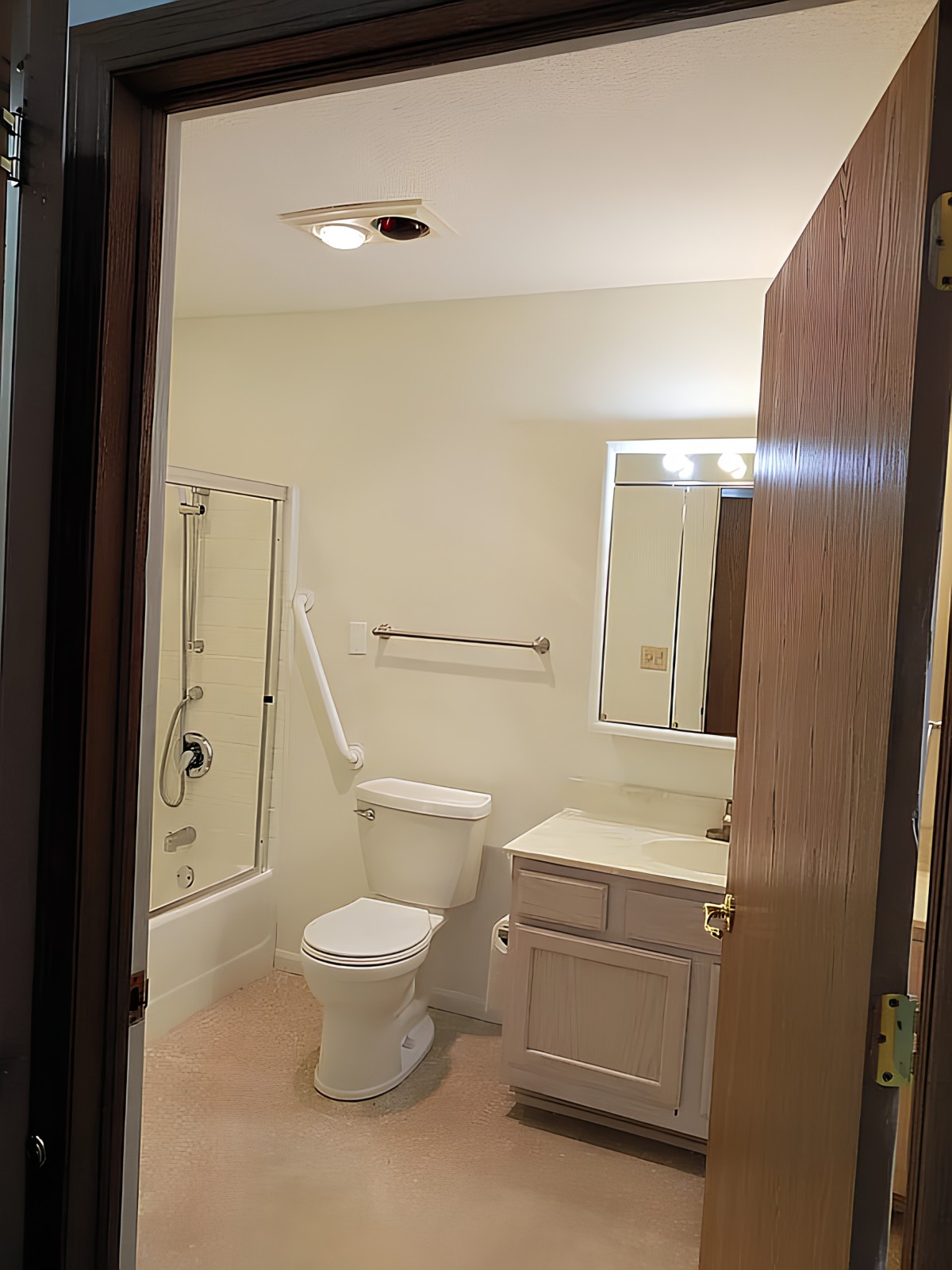 A view of a small bathroom with essential fixtures including a toilet, sink, and shower.