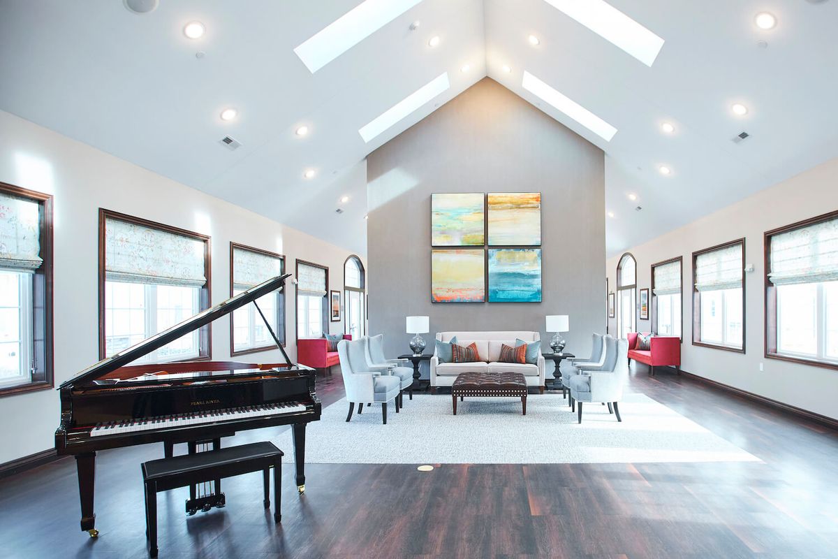 A modern living room with a grand piano, vaulted ceiling, and contemporary artwork.