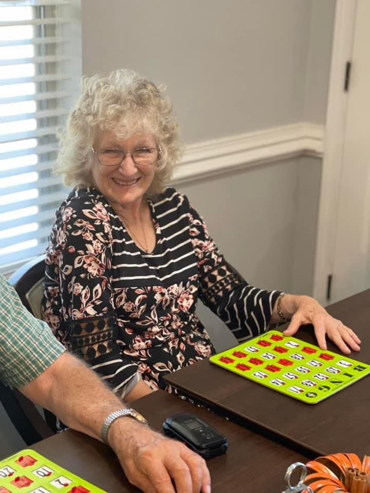 A smiling woman playing bingo indoors.