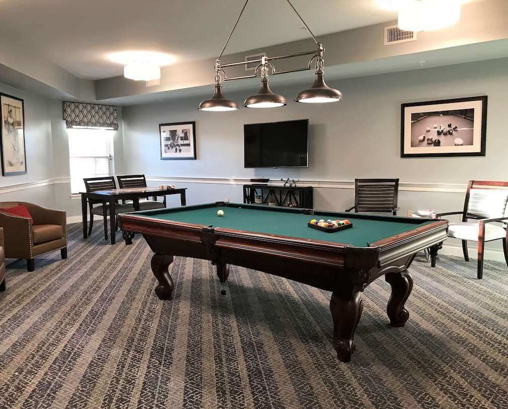 A cozy game room featuring a pool table, seating area, and a wall-mounted television.
