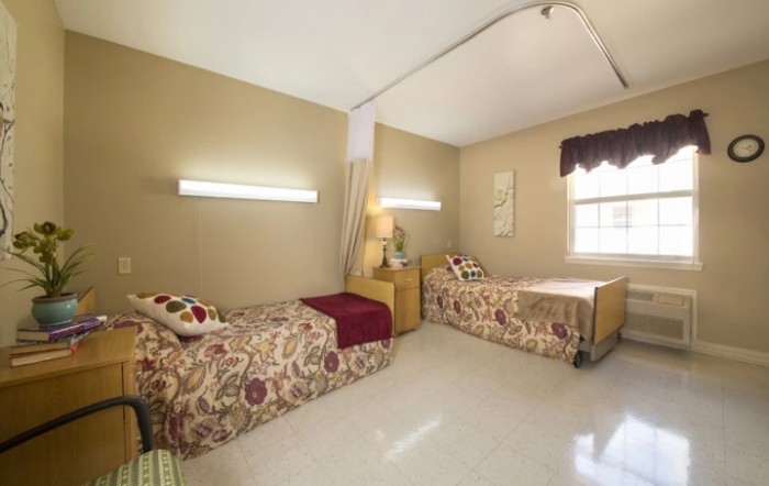 A simple bedroom with twin beds and warm lighting.