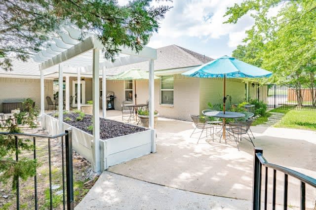 A sunny backyard patio with seating areas and a garden.