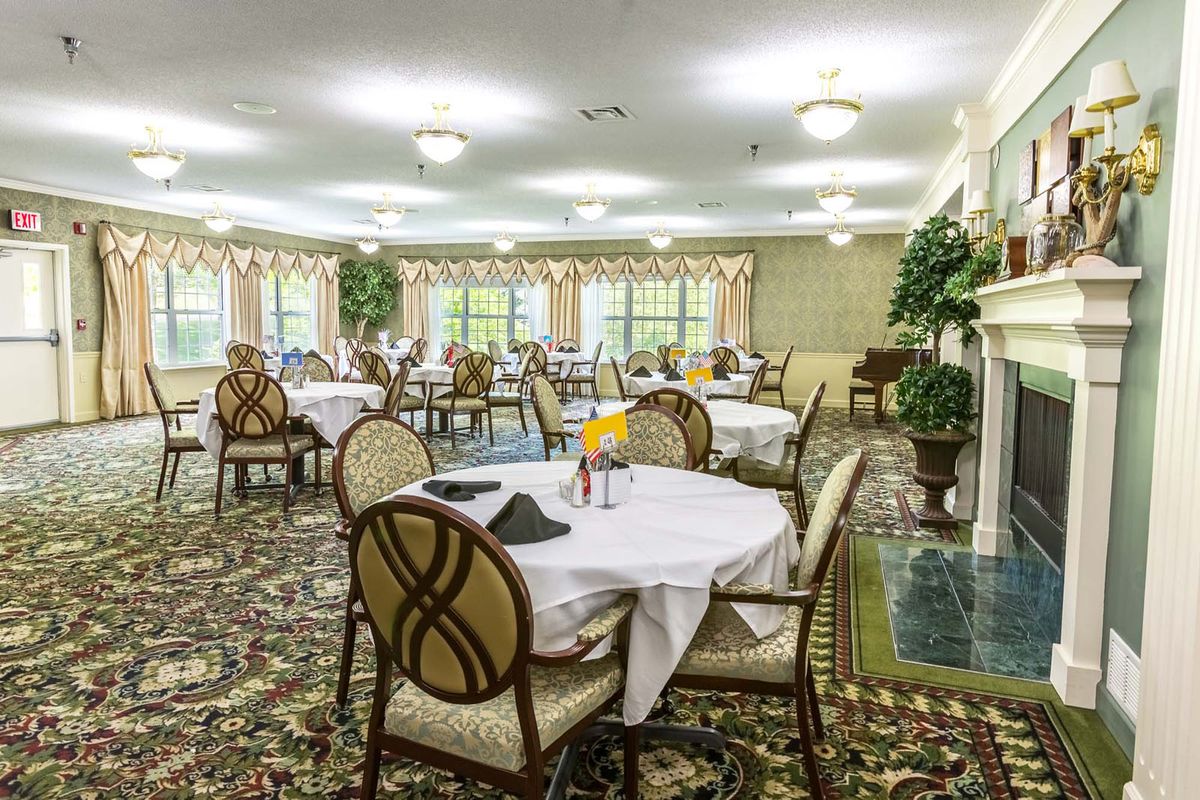 A well-furnished dining room with multiple tables and chairs, featuring elegant decor and lighting.